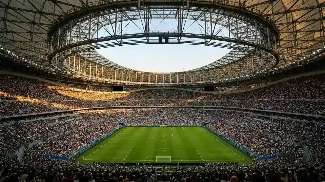 Vue d'un stade de football moderne rempli de spectateurs, vu depuis les tribunes hautes en fin de journée